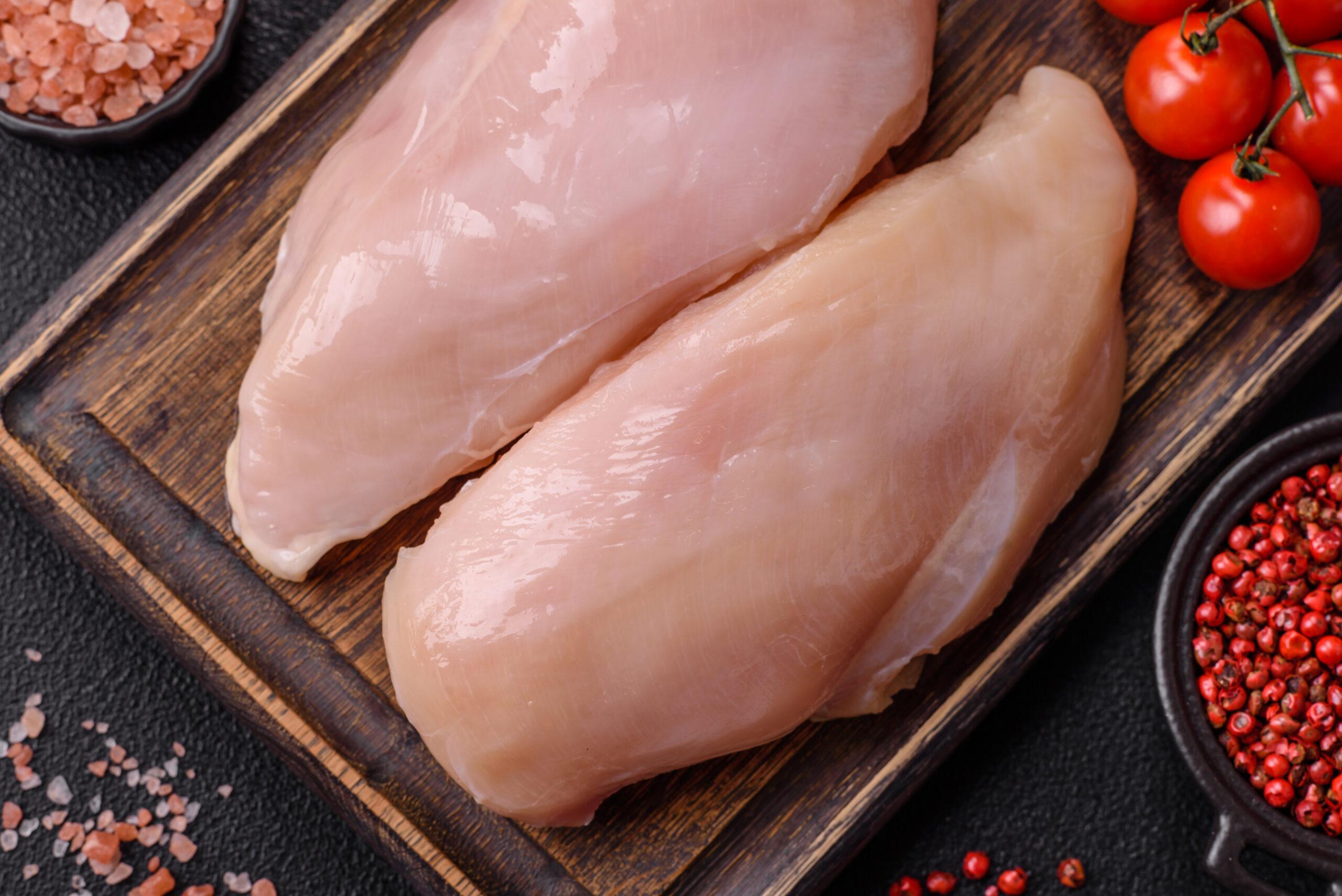 Pieces of raw chicken or turkey fillet with salt, spices and herbs on a dark concrete background